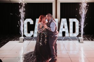 Couple's first dance lit by cold sparklers with giant illuminated letters spelling their names behind them