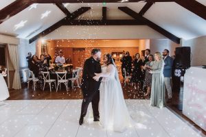 First dance under a confetti shower in a barn-style venue with star projections on the ceiling
