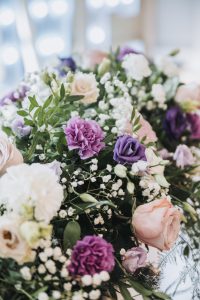 Detail shot of a bridal bouquet with peach roses, purple carnations and gypsophila