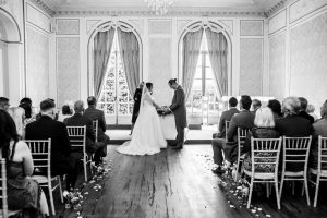 Black and white wedding ceremony in an elegant period room with arched windows and chiavari chairs