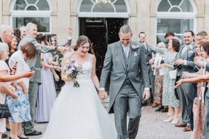 Bride and groom exiting the venue through a confetti shower thrown by guests lining the path
