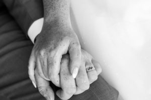 Black and white close-up of a bride's hand resting on the groom's, wedding ring detail